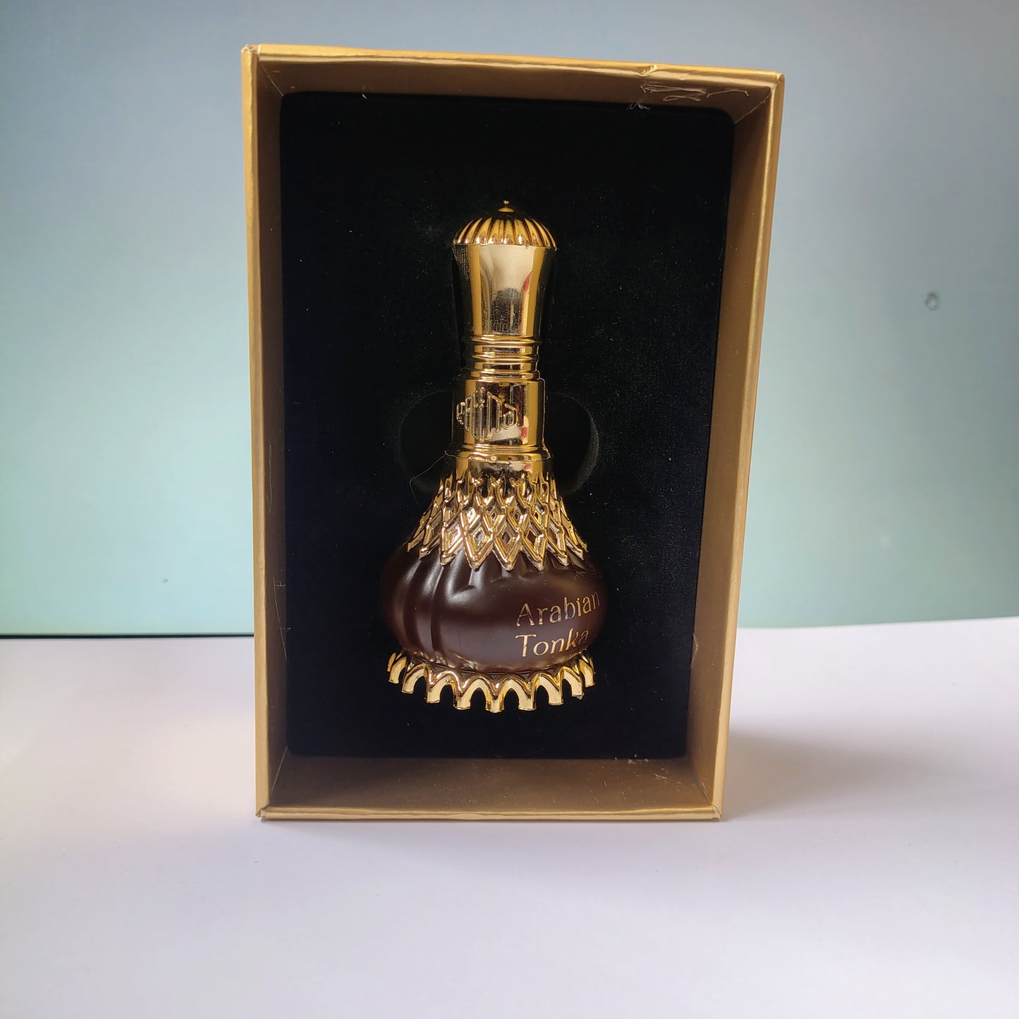 Decorative bottle with gold accents in a box on a light blue background